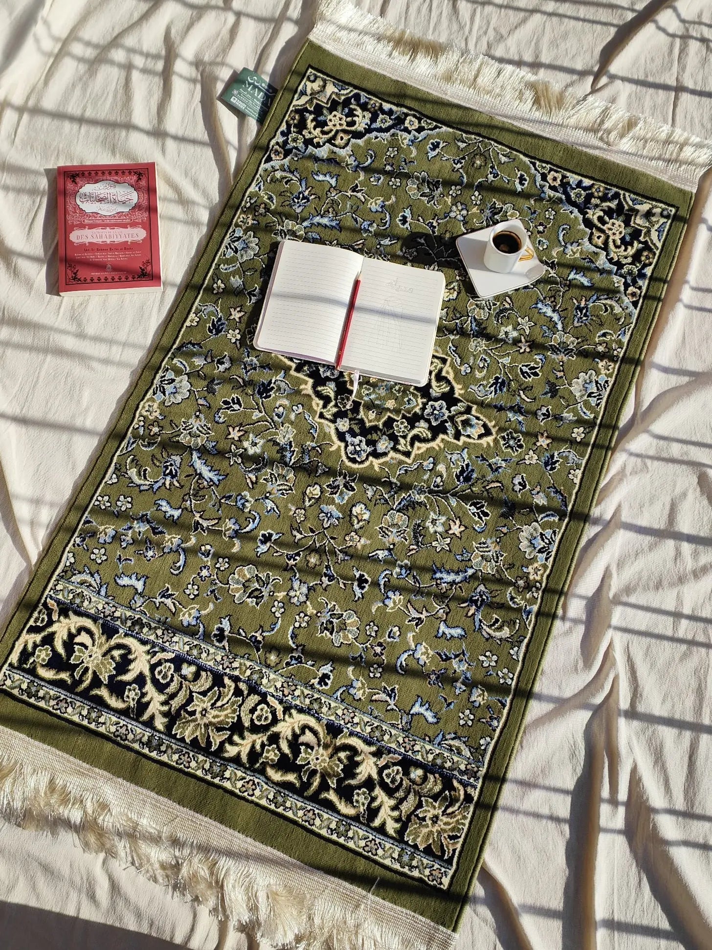 tapis de prière avec un café, livre et carnet